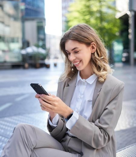 vertical-shot-smiling-businesswoman-looking-smartphone-app-sending-message-mobile-phone-ode_1258-118769